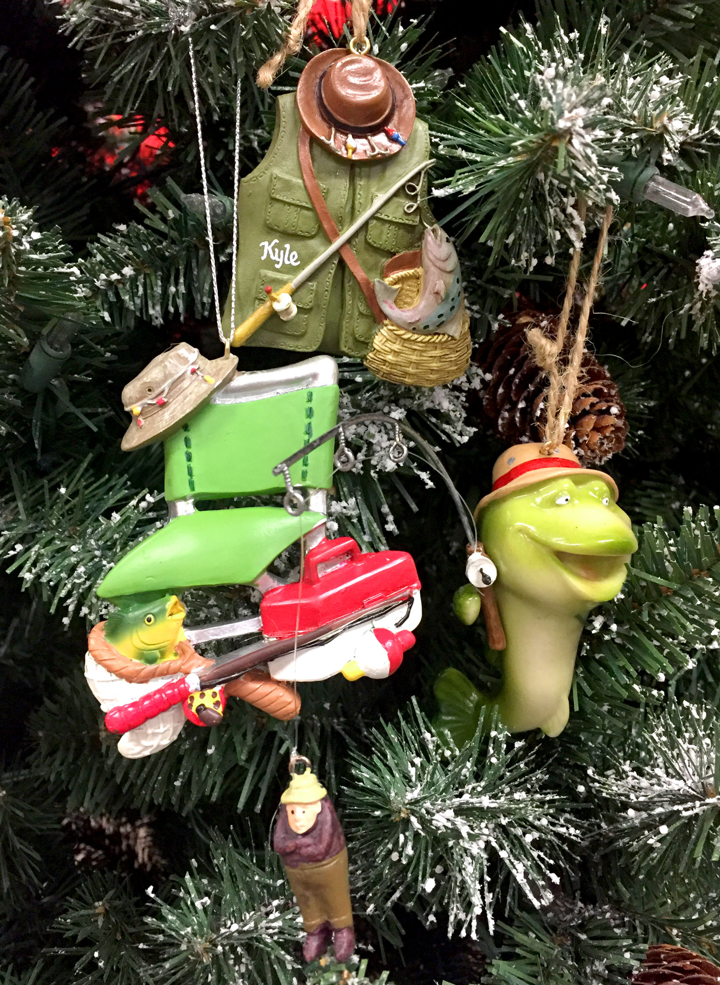 Three fishing ornaments: One with a fishing chair, another with a fisherman's vest, and a third with a large fishing pretending to reel in a human | OrnamentShop.com