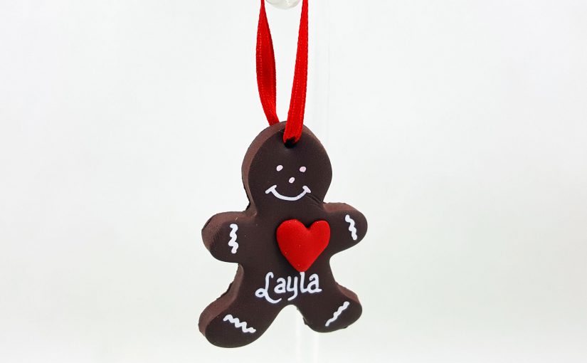 A DIY gingerbread man ornament with a red heart and white features, hung with a red ribbon | Ornamentshop.com