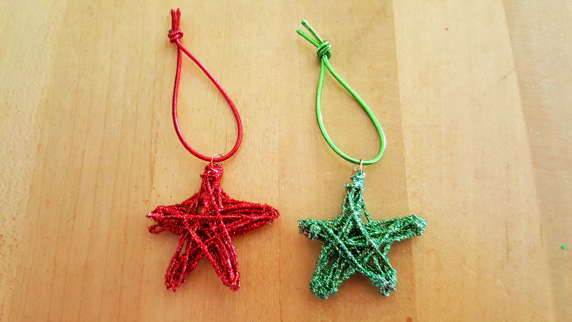 A red and green DIY star ornament side by side on a counter | OrnamentShop.com