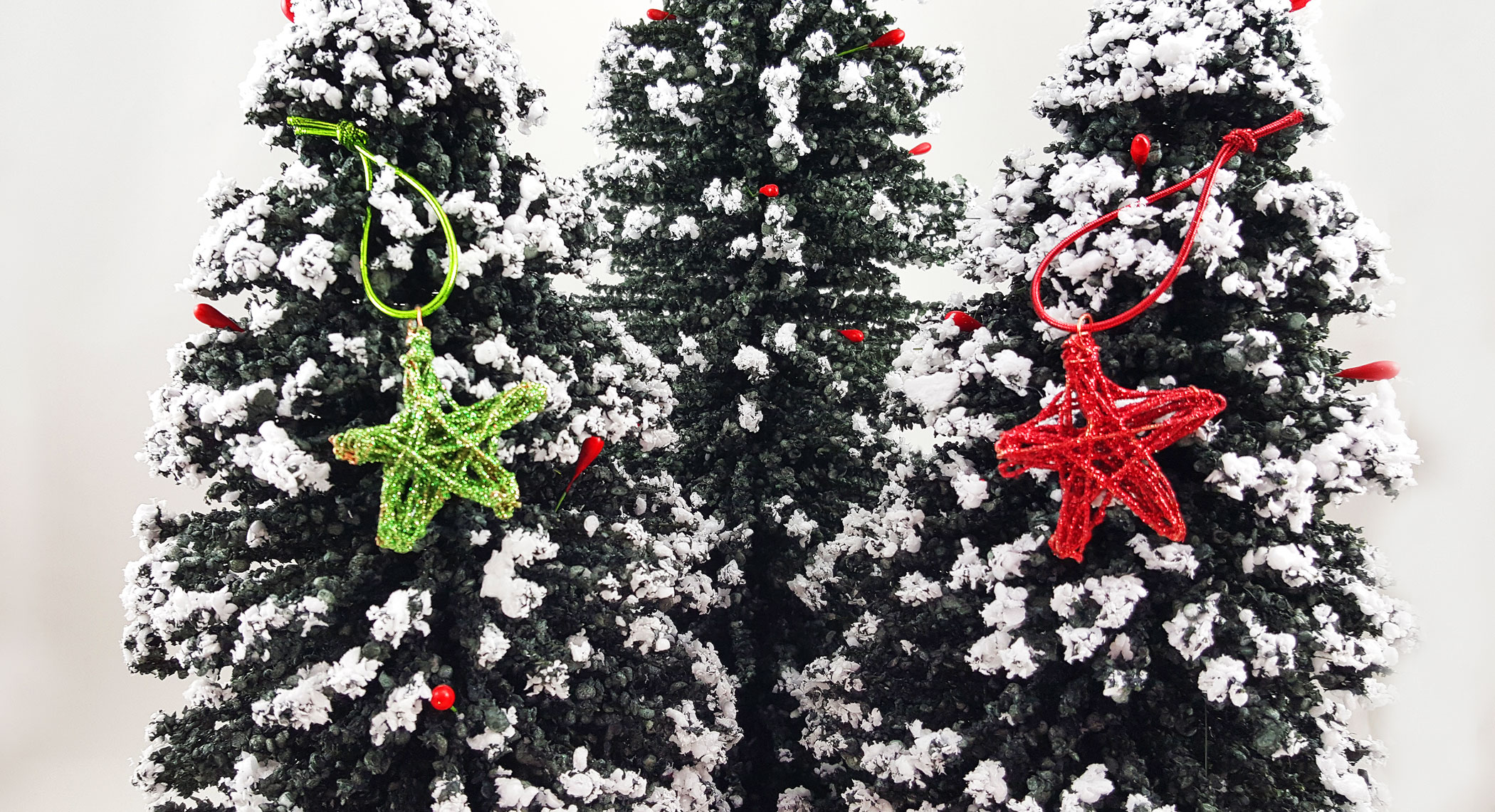 A red and green DIY star ornament hangs on miniature trees | OrnamentShop.com