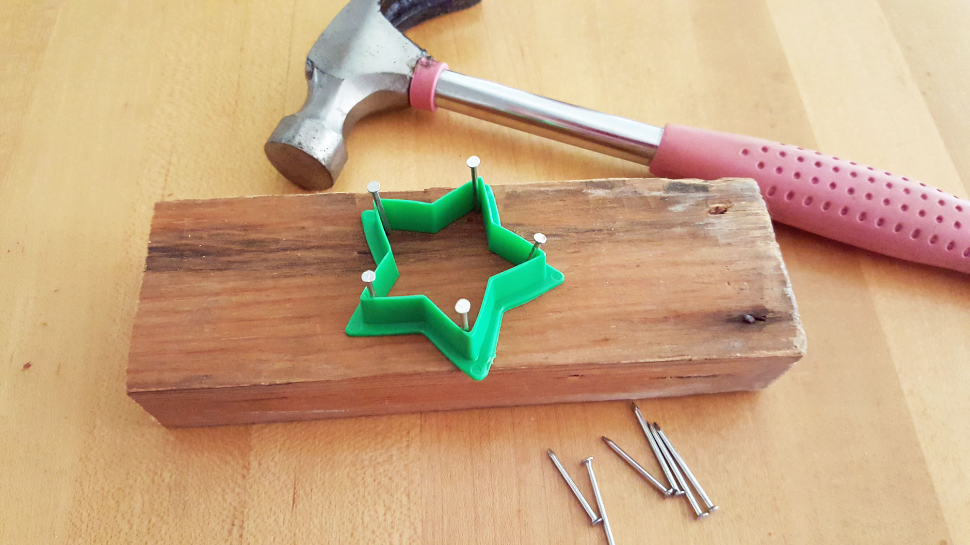 Step 1 is to place a cookie cutter on a block of wood, and hammer nails into each point | OrnamentShop.com 