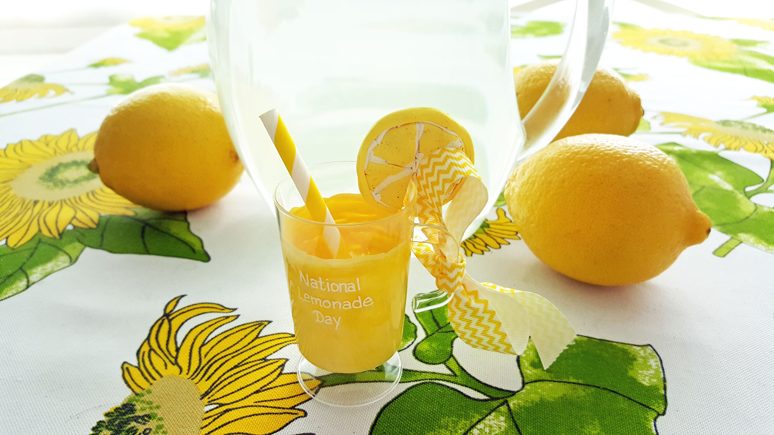 A cup of lemonade ornament sits on a picnic table next to a pitcher of lemonade. | OrnamentShop.com