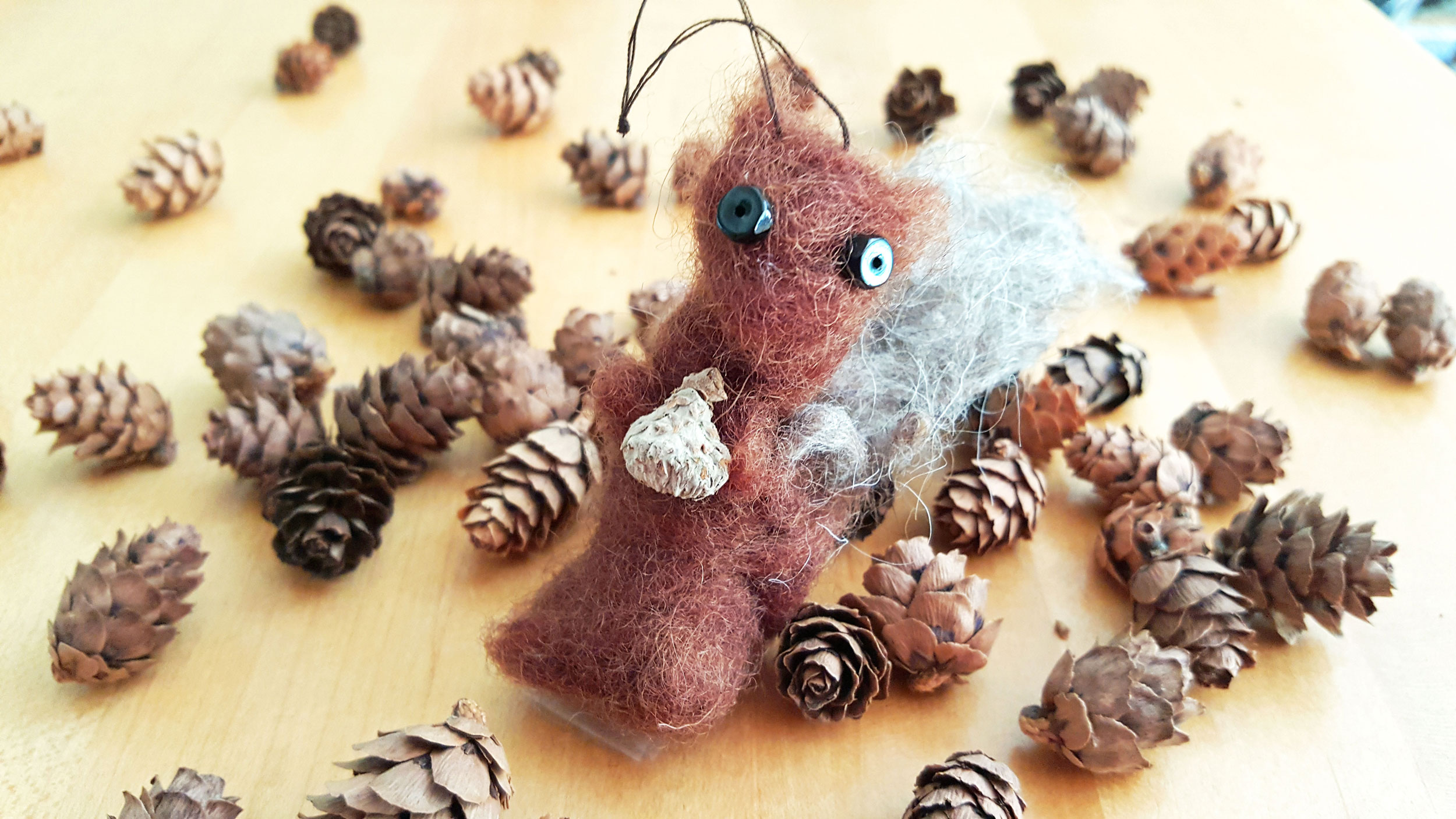 the final DIY squirrel felted ornament surrounded by little acorns. | OrnamnentShop.com