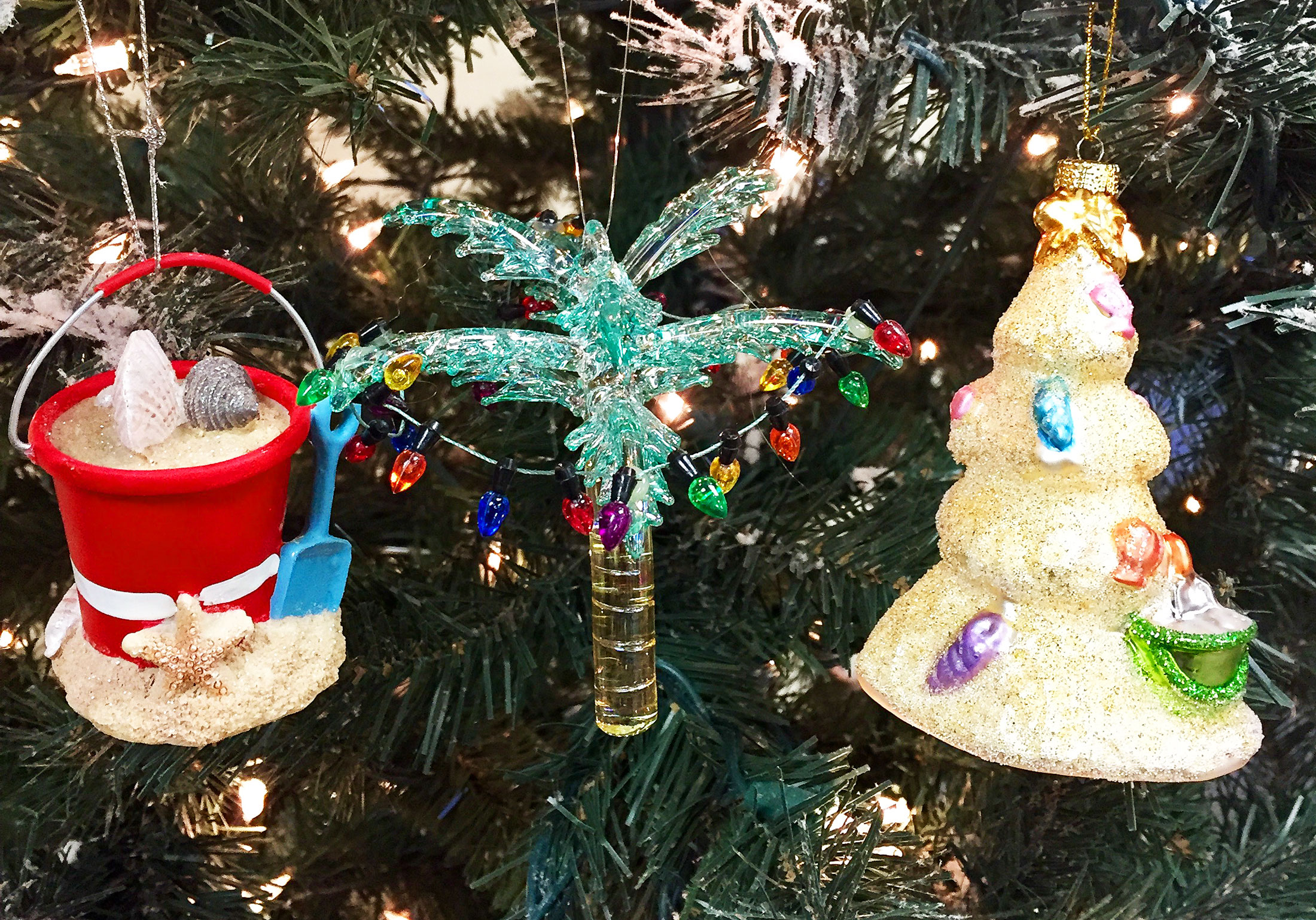 A palm tree with lights ornament, a sand castle ornament, and a sand bucket ornament | OrnamentShop.com