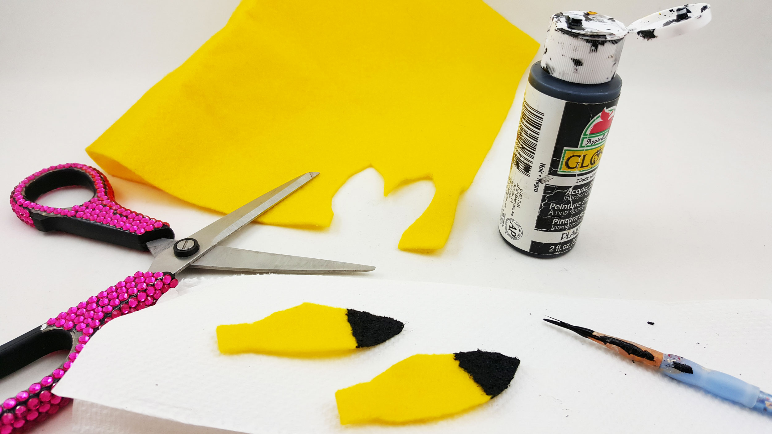 The second step to make a Pikachu ornament is to cut the ears out of the fabric and paint the tips black. | OrnamentShop.com