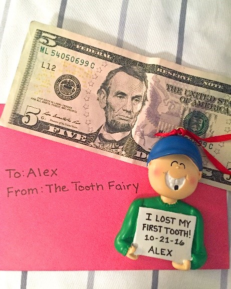 An ornament with a boy holding a sign and a gap in his smile that reads: I lost my first tooth! | OrnamentShop.com