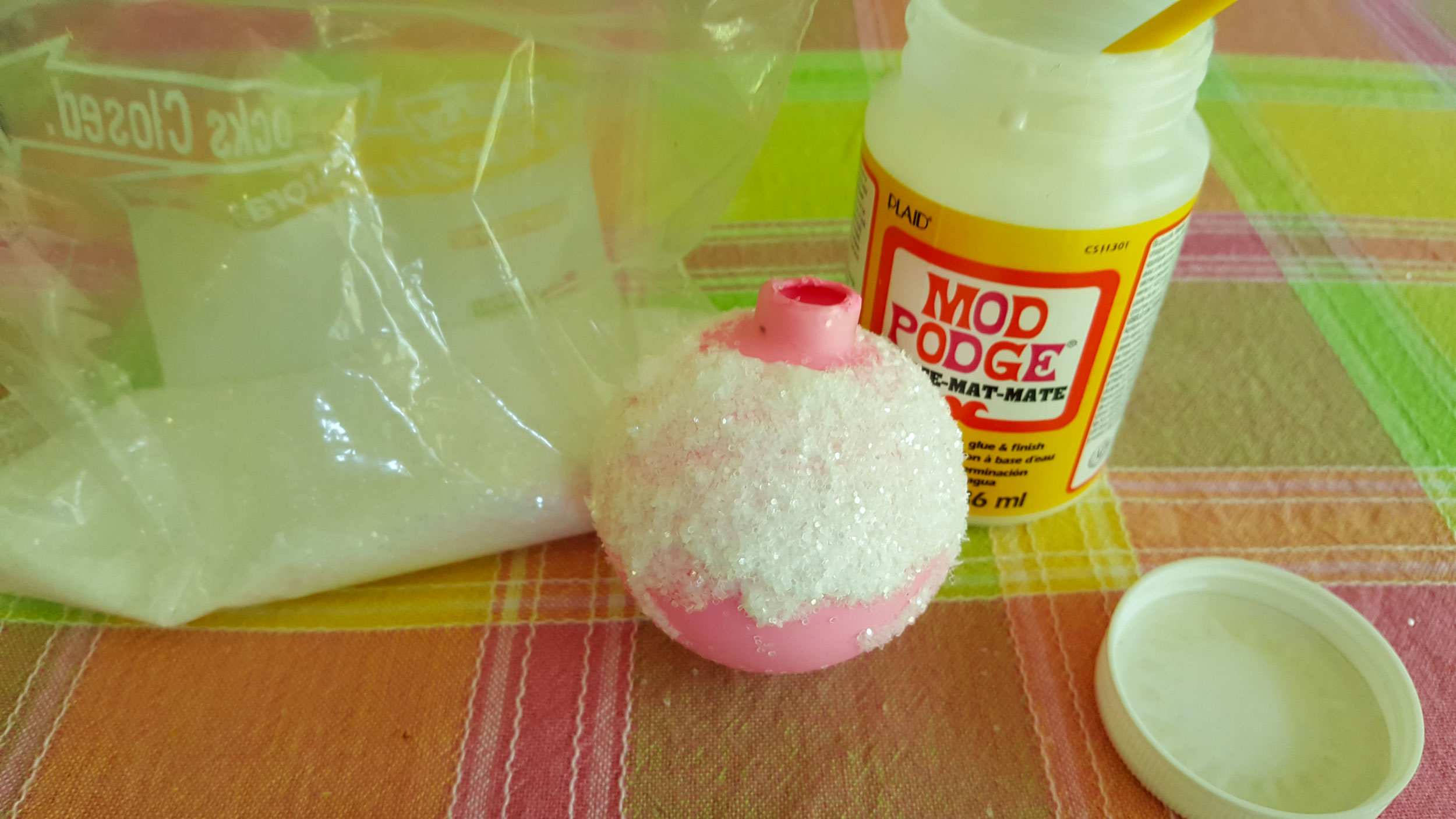 Step 5 is to use Modge Podge to coat the top of the glass ball to look like frosting, then shake glitter on it. | OrnamentShop.com