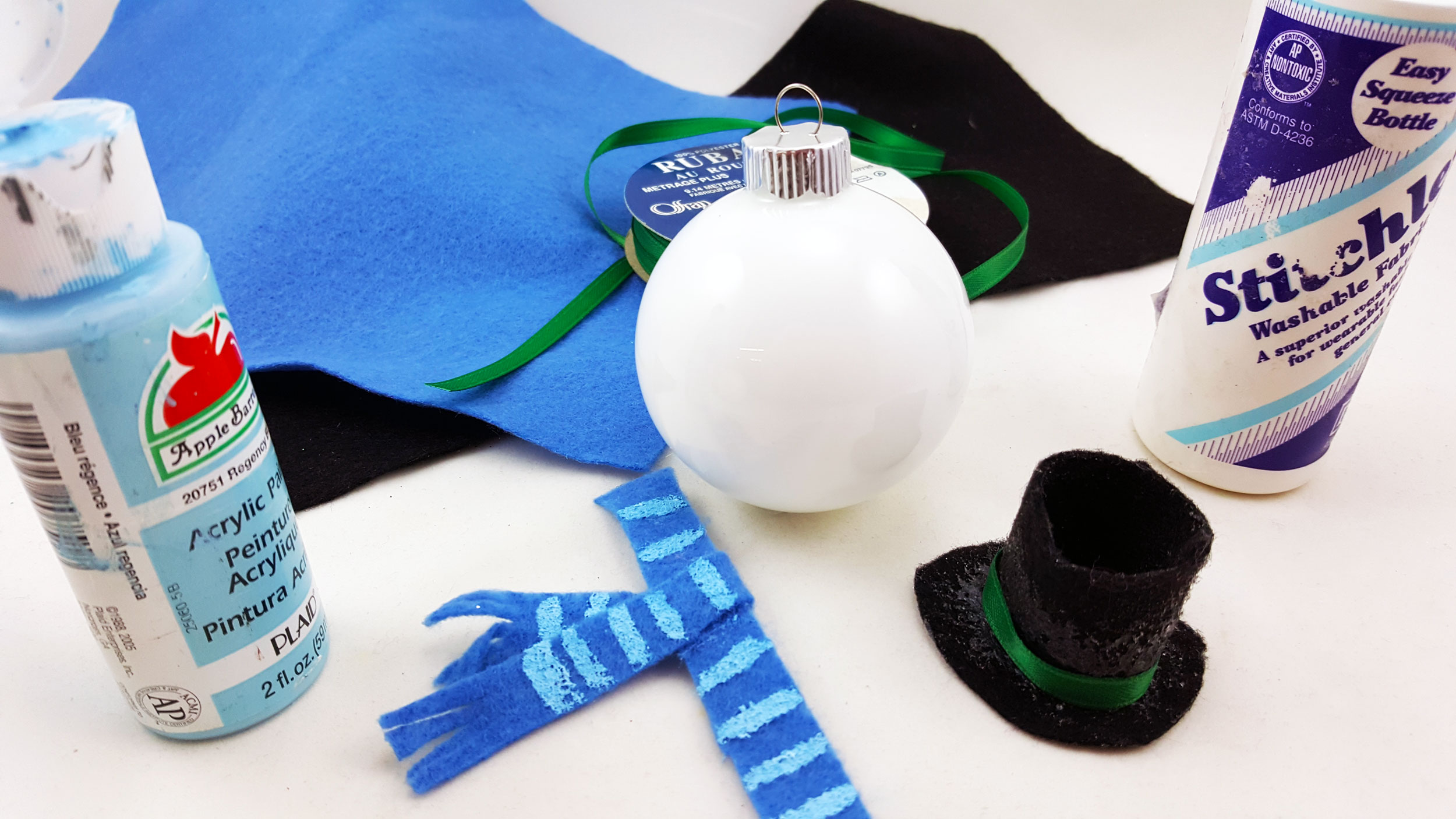For Chilly, cut black felt pieces for the base of the hat, circumference of the hat, and top of the hat. Then use a green strip for the hat's band, two pieces of blue felt for the scarf, and then use paint to make light stripes on the scarf. | OrnamentShop.com