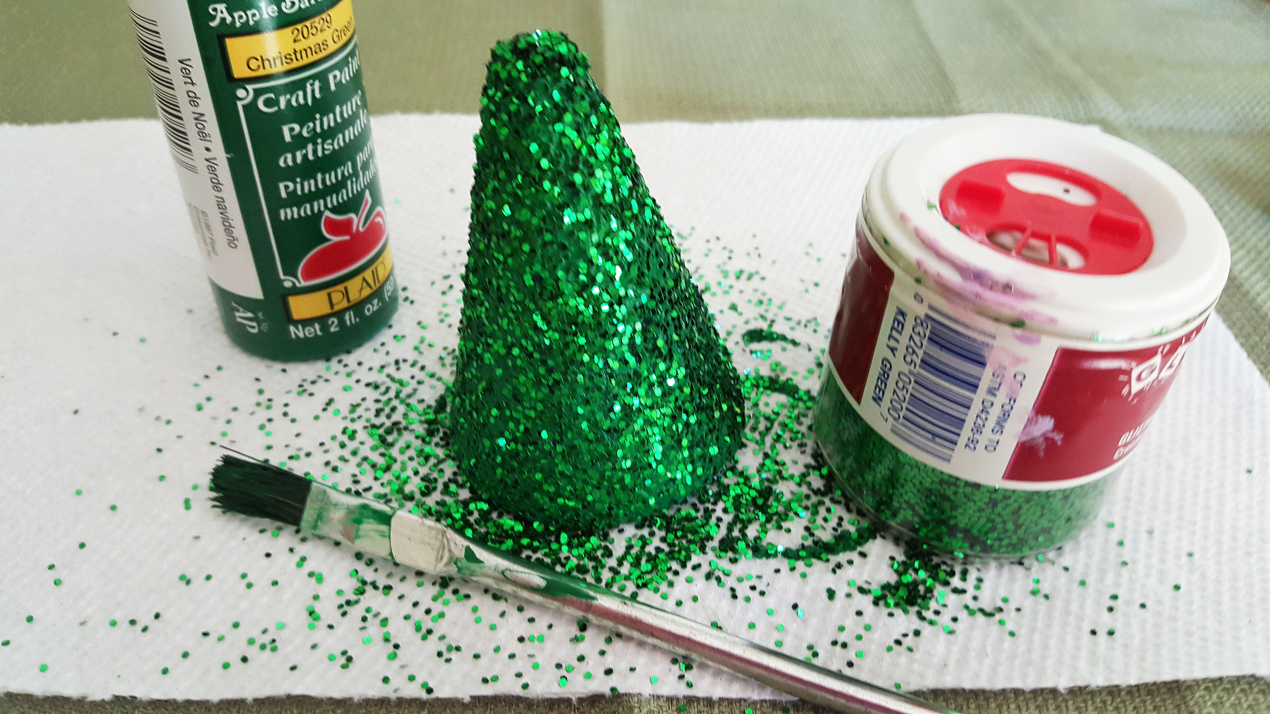 Step 1 to make the miniature Christmas tree craft for kids is to paint the Styrofoam cone with green paint and shake green glitter over it. | OrnamentShop.com