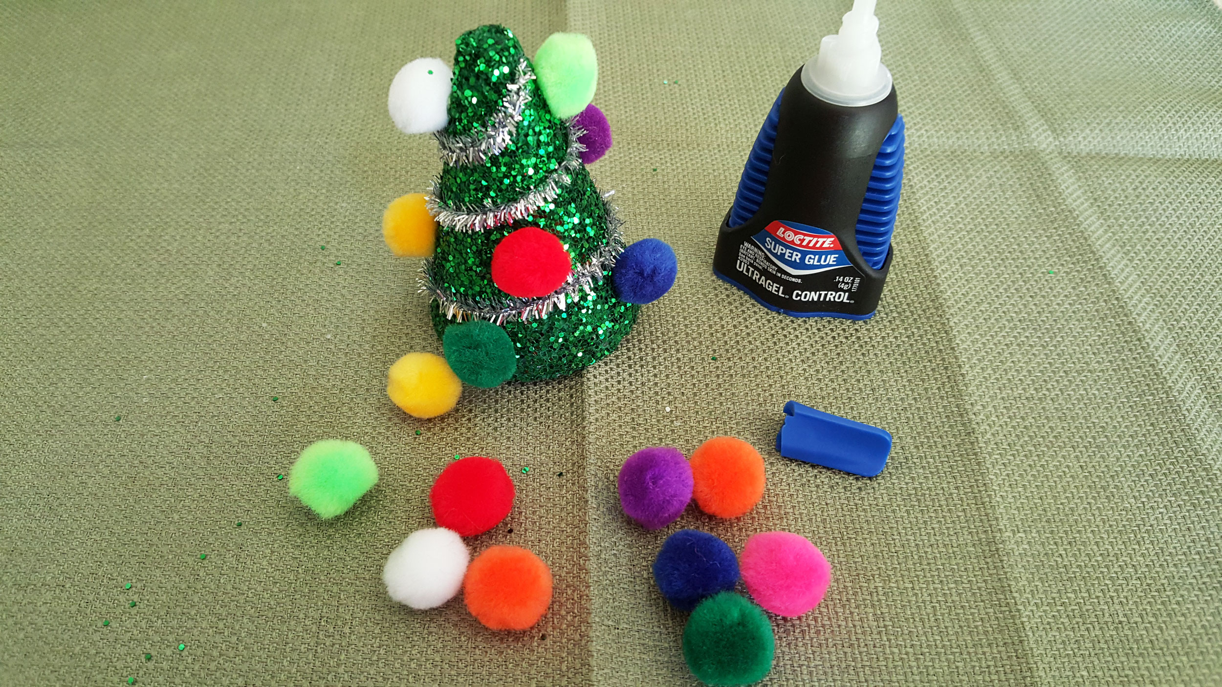 Step 4 to make the Christmas Craft For Kids is to glue pom poms on the tree like ornaments. | OrnamentShop.com
