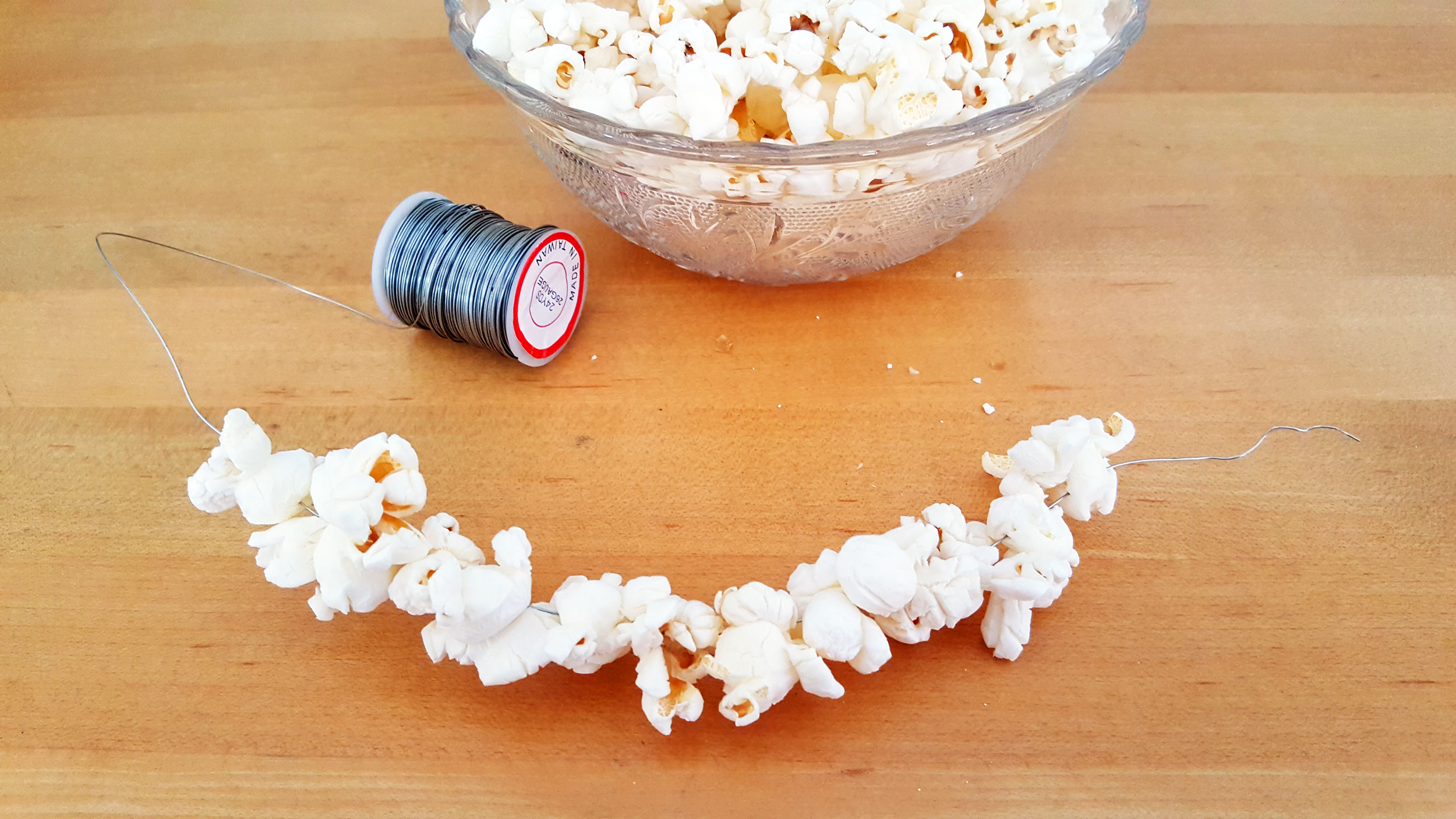 Step 1 is to string your popcorn along the wire. | OrnamentShop.com