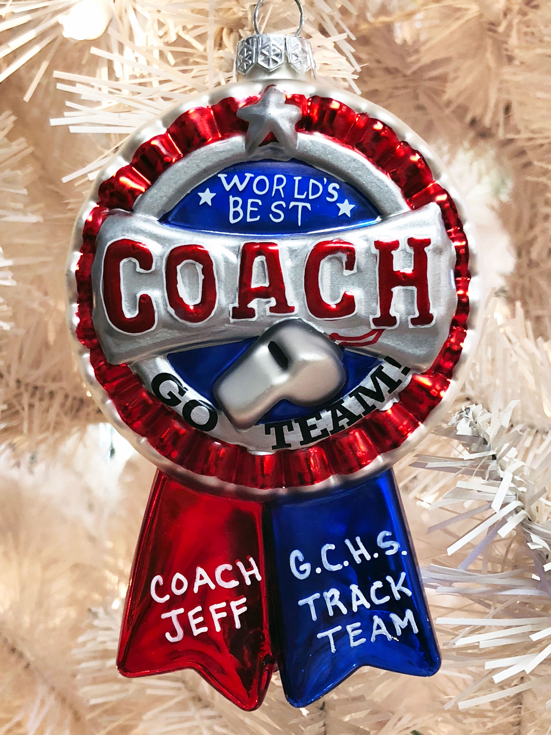 A blue ribbon ornament with World's Best Coach written on it, and it can be personalized with your coach's name. | OrnamentShop.com