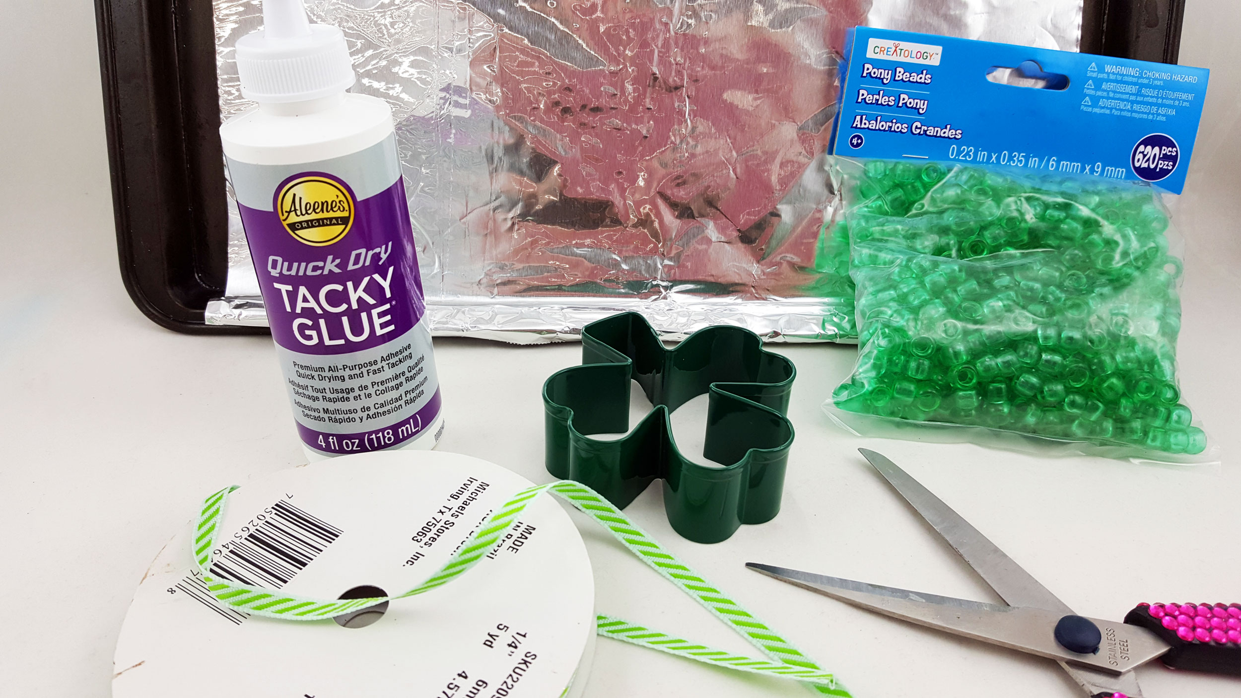 Supplies to make your own DIY St. Patrick's Day ornament include a cookie sheet, a metal cookie cutter, green pony beads and a paint marker. | OrnamentShop.com