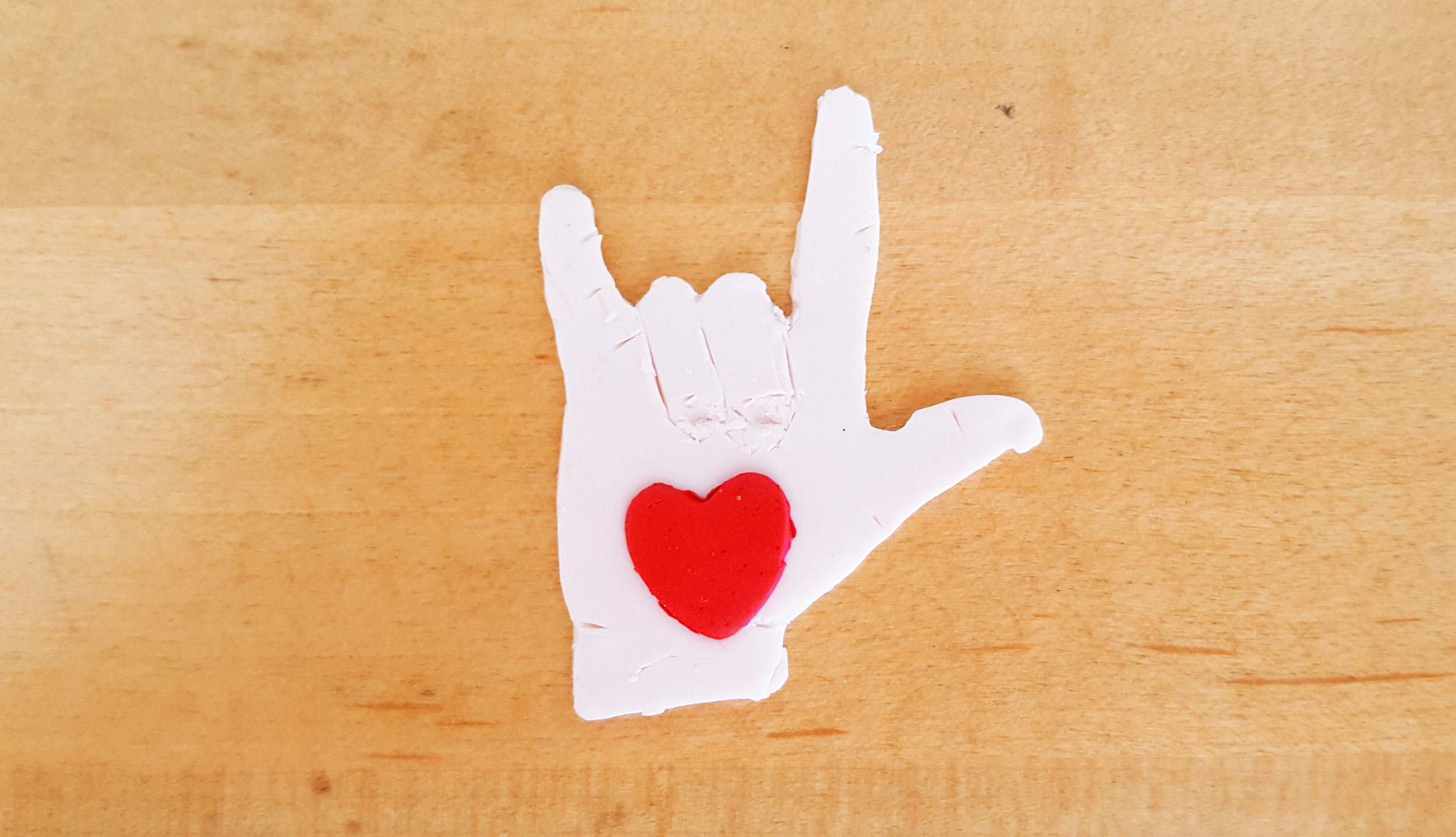 Red heart on clay "rock out" hand| OrnamentShop.com