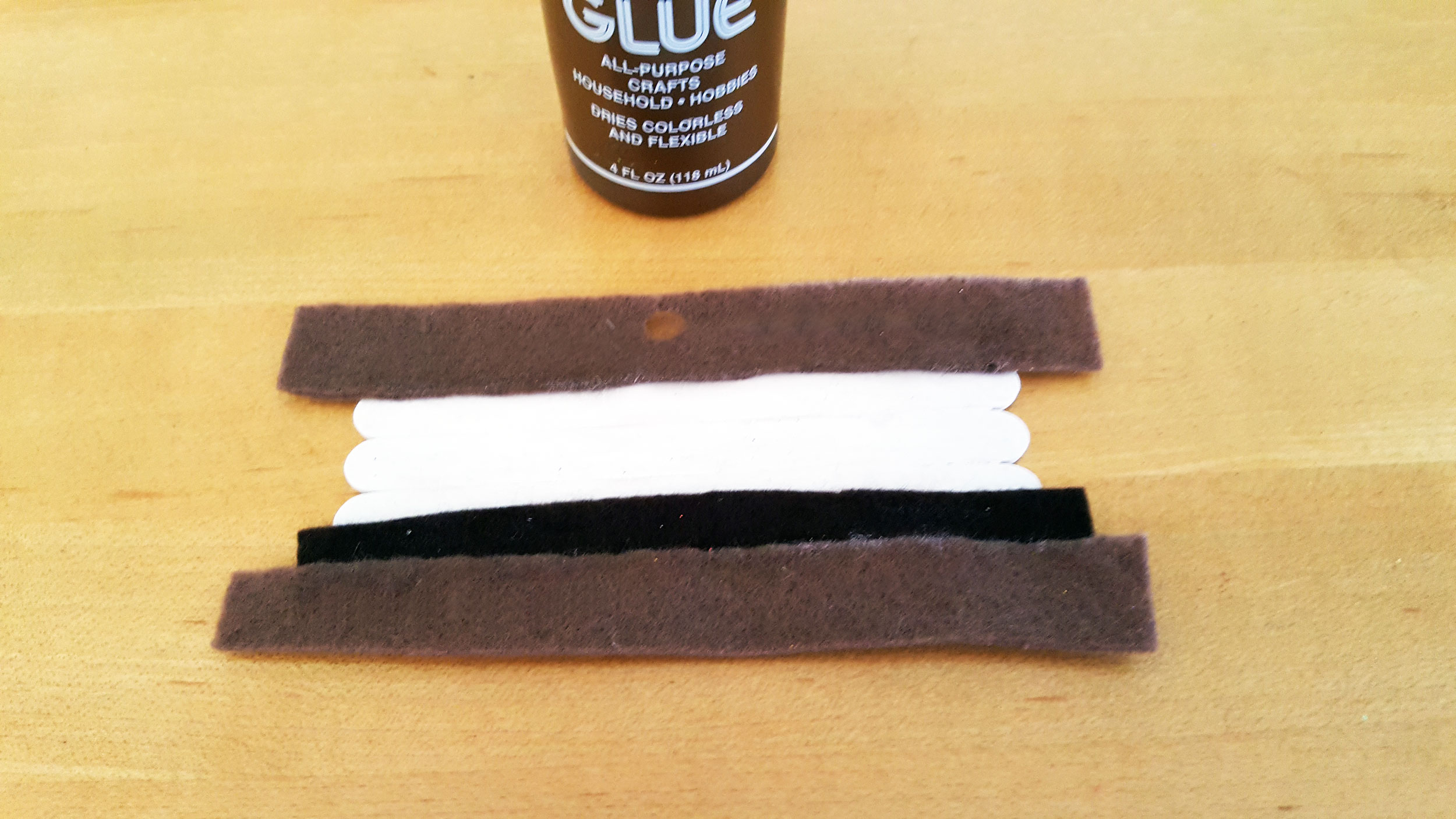 Step 5 is to glue the marshmallow piece with the chocolate piece overlapping on the bottom stick and then graham cracker overlapping on either side. | OrnamentShop.com