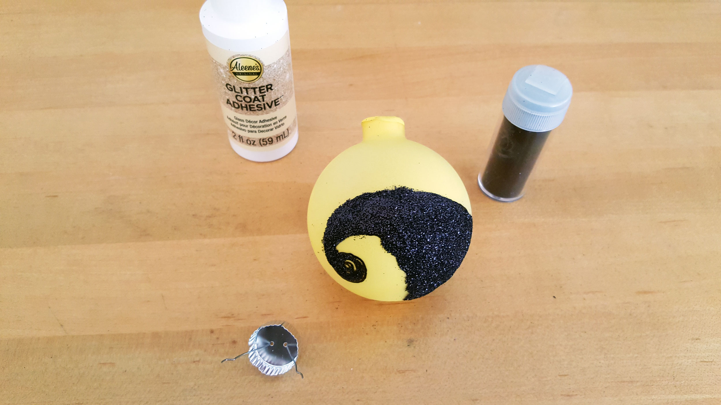 Nightmare Before Christmas Ornaments glue and shake black glitter to fill the ledge outline | OrnamentShop.com