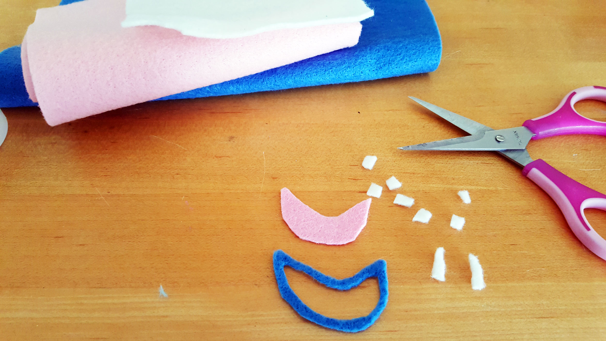 Smallfoot DIY Step 9 is to cut the mouth with pink felt and a bigger shape with blue felt, then overlap the two for blue lips. Then cut the teeth into squares with two bottom fangs. | OrnamentShop.com