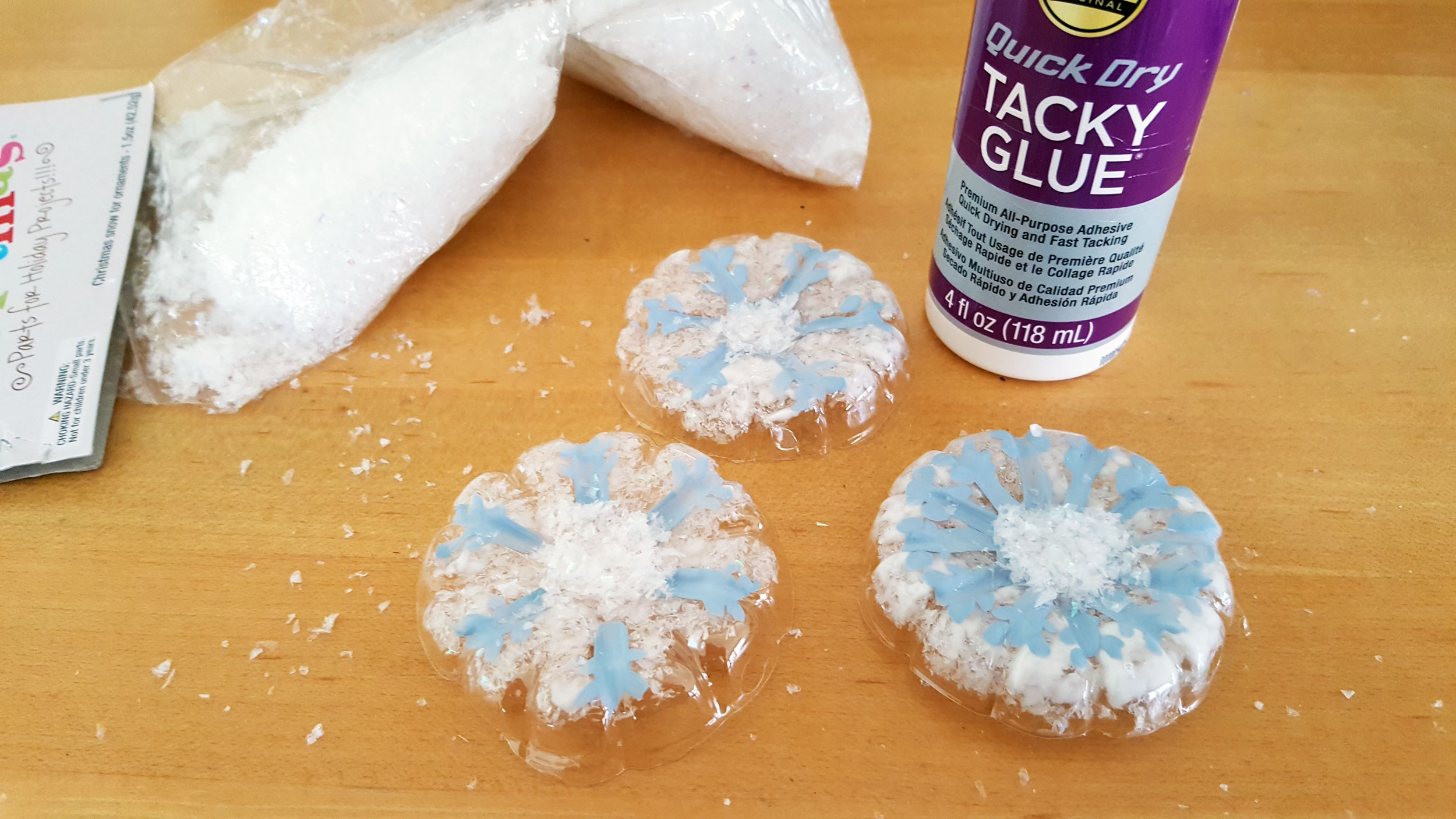 Snowflake Ornaments Step 7. Add glue and glitter embellishments to fill the indented center on the outside of the plastic bottle craft.&nbsp;| OrnamentShop.com