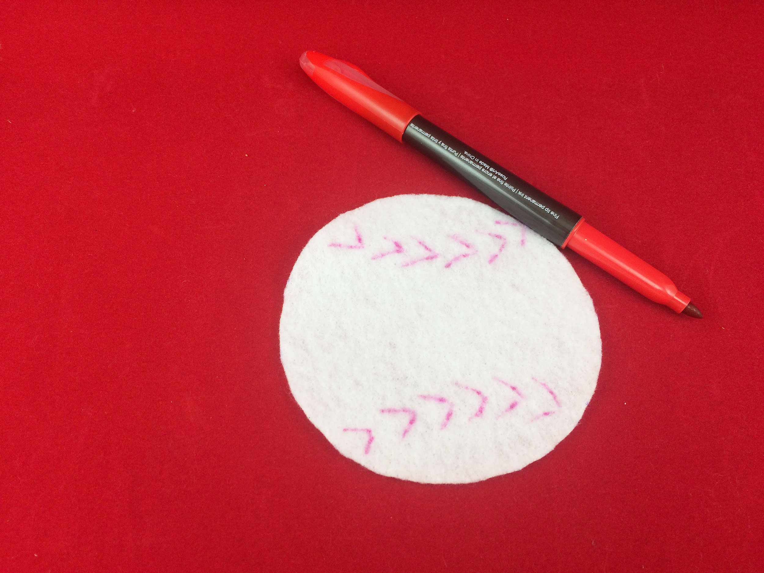 Cut out white felt circle. Red baseball stripes drawn with red marker. | OrnamentShop.com