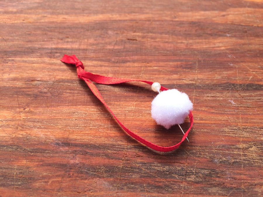 Pin hanging ribbon and pom pom to red foam cap | OrnamentShop.com